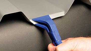 Umkantung des Trapezbleches mit einer Klemp­ner-Falzzange, um das Wasser besser in die Dachrinne zu leiten